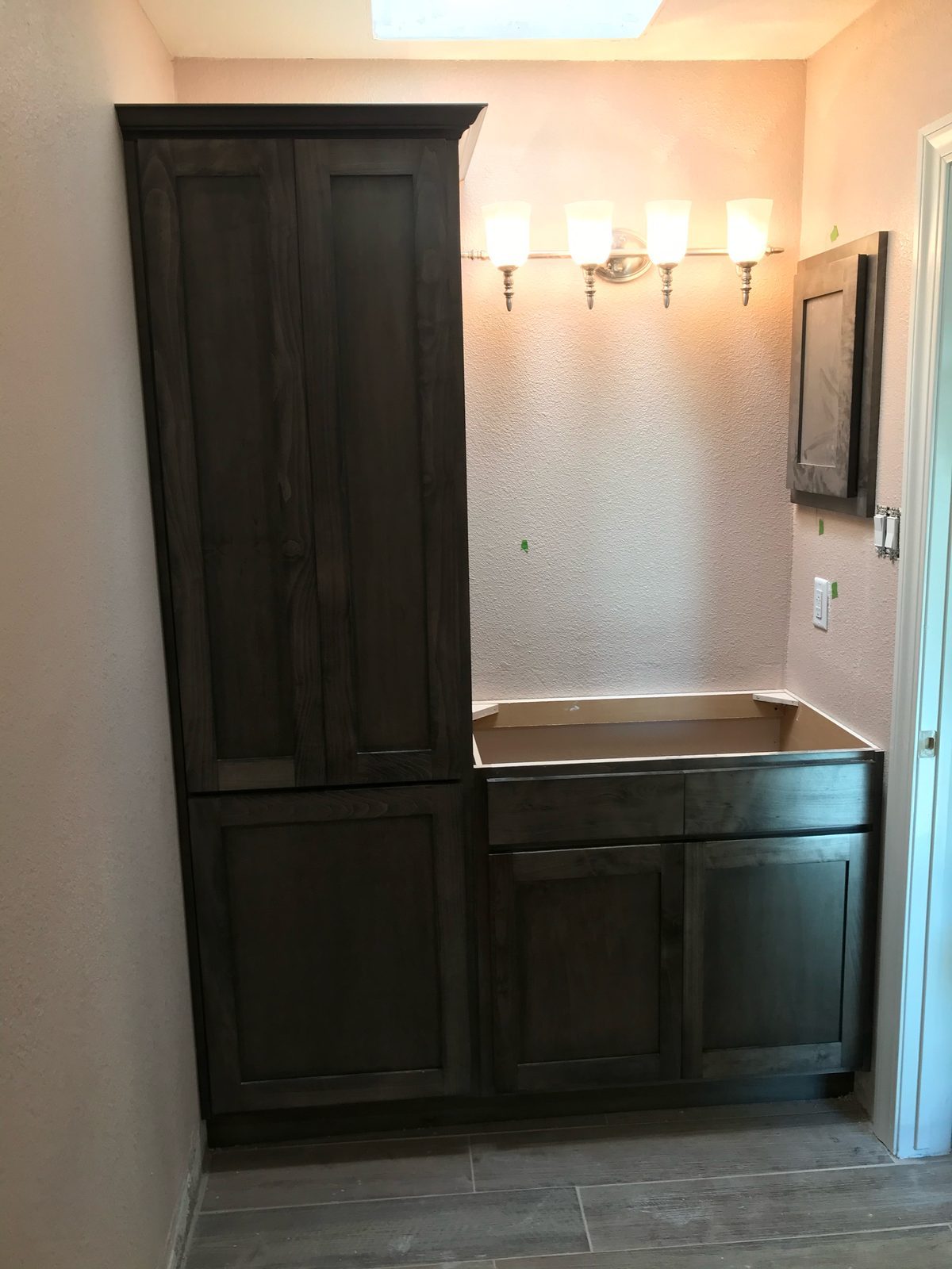Dark tall linen cabinet beside a bathroom vanity