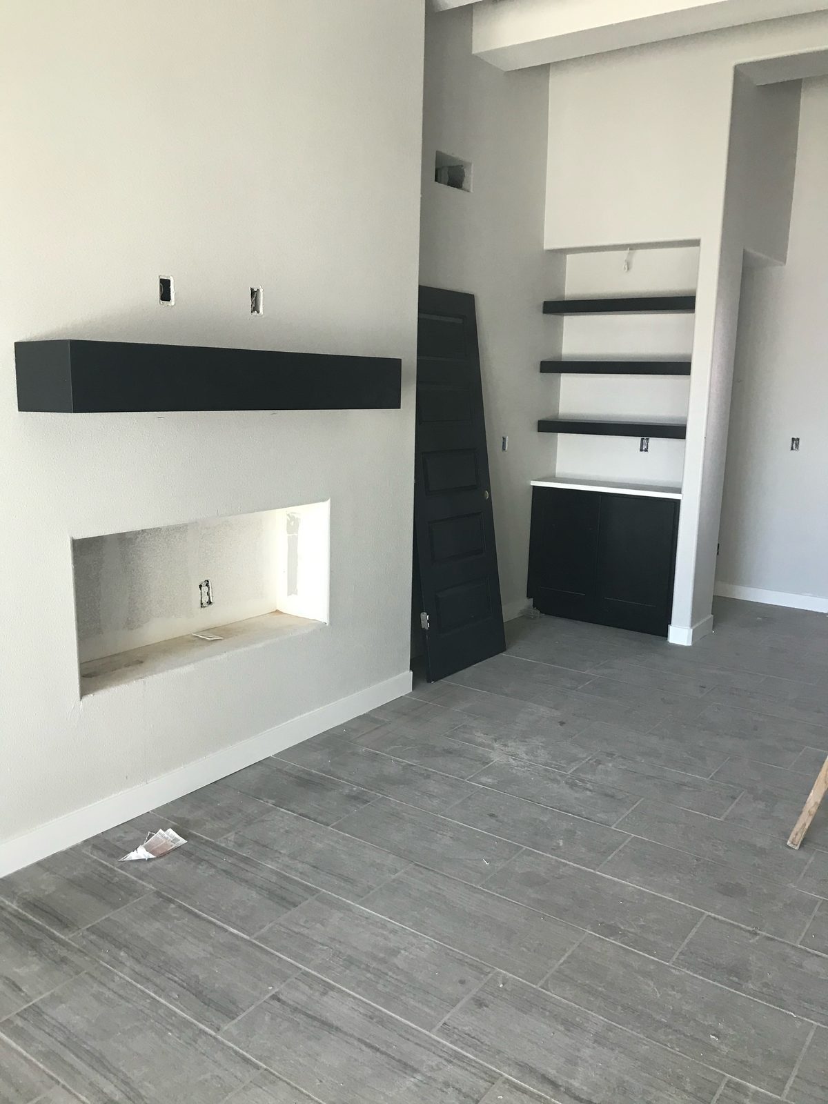 Black floating mantel with built-in shelves and cabinet