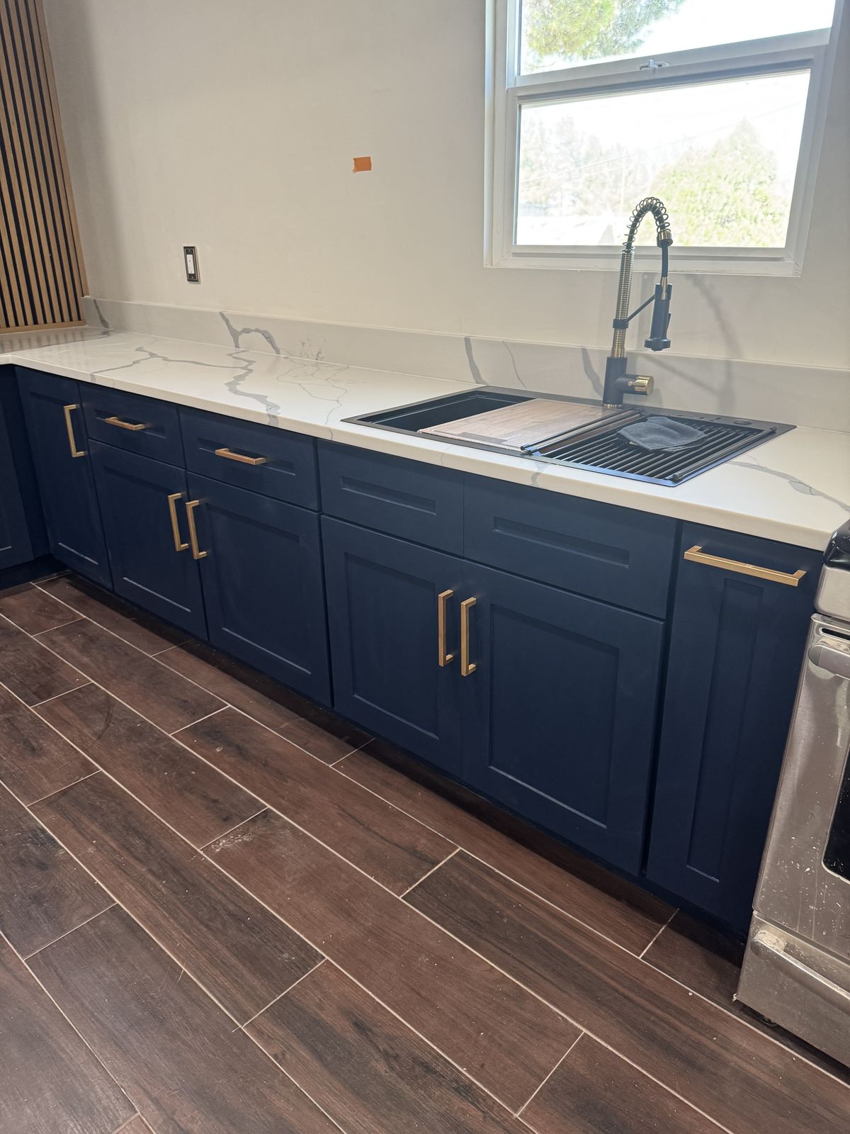 Navy blue shaker lower cabinets with gold pulls and white quartz countertop