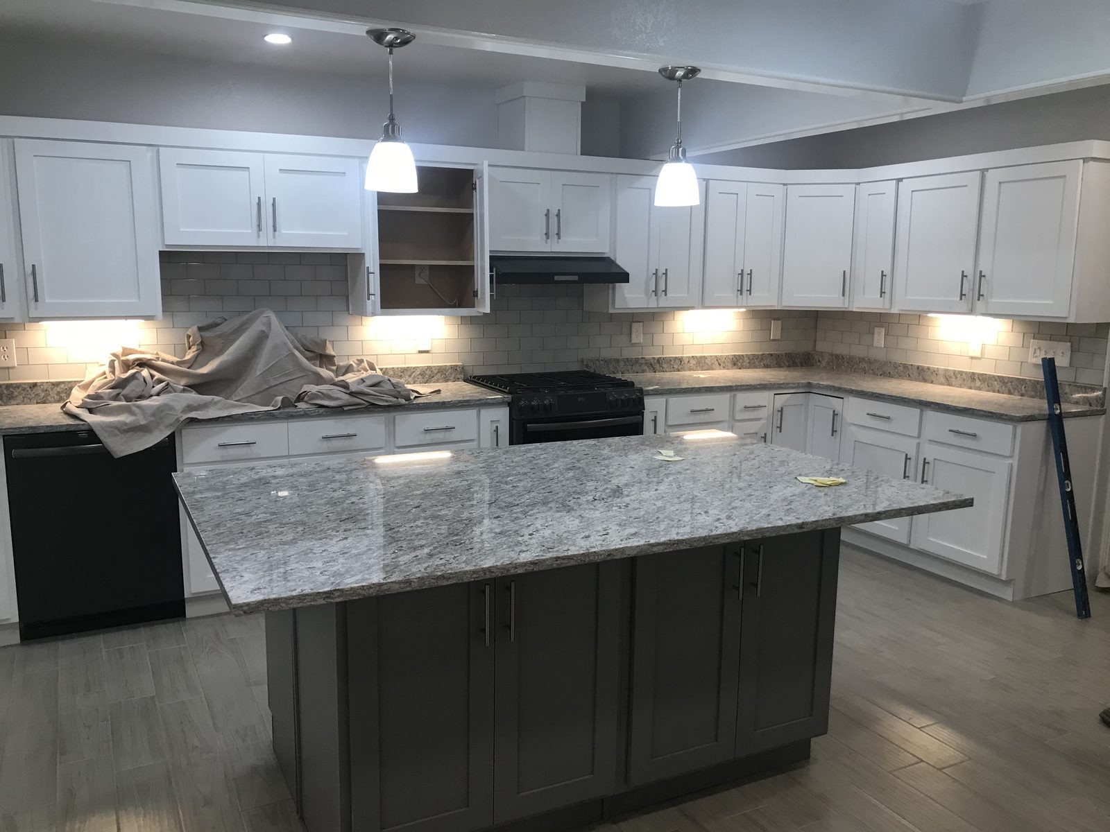 White shaker kitchen with gray island, granite and subway tile
